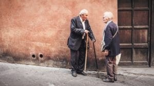 Older man and older woman facing each other on the street