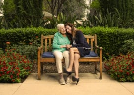 Resident Lorraine Beckenstein and Larissa Stepanians MS '01 embrace on a bench in a courtyard of the LA Jewish Home