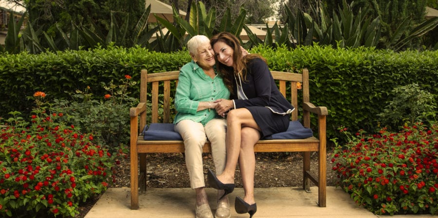 Resident Lorraine Beckenstein and Larissa Stepanians MS '01 embrace on a bench in a courtyard of the LA Jewish Home