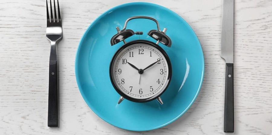 photo of clock on empty plate fasting concept