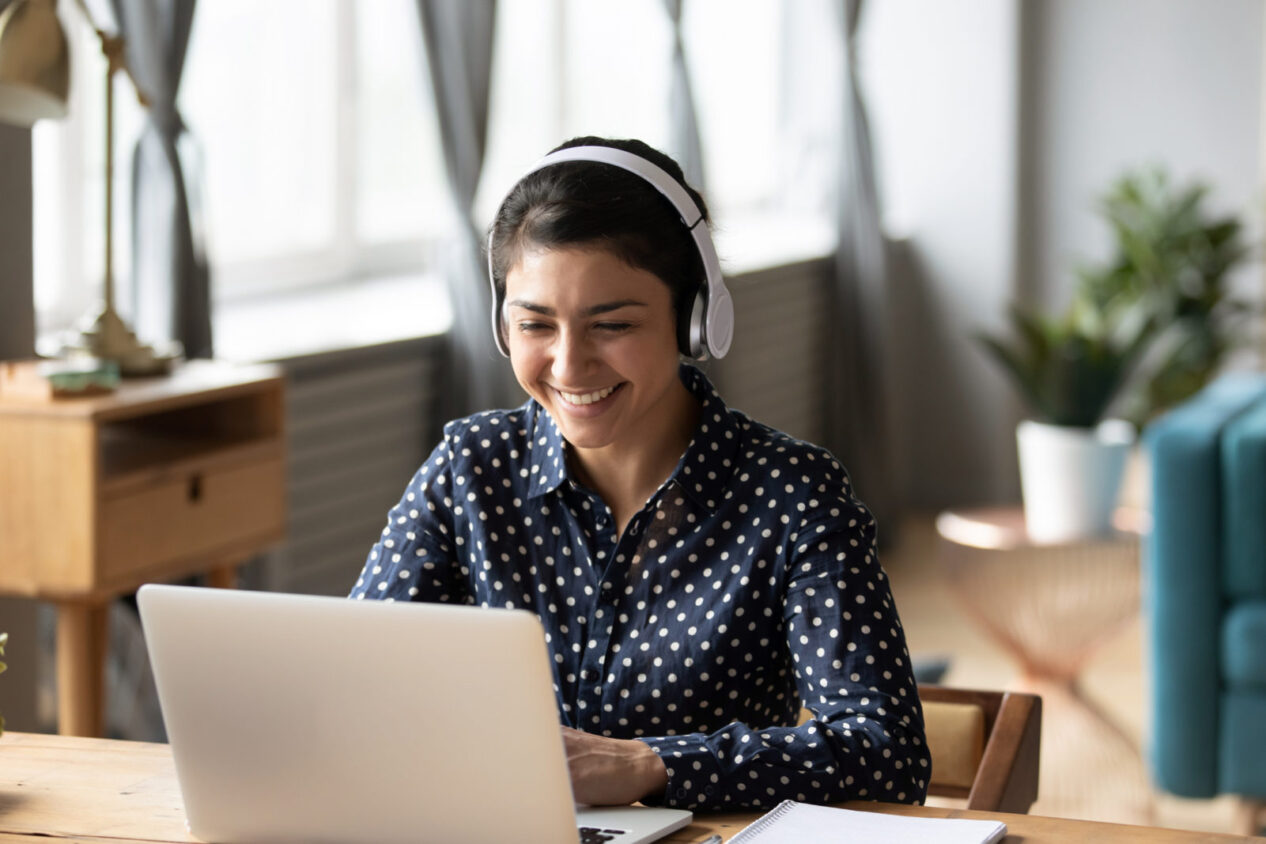 Happy student wearing headphones watching her laptop