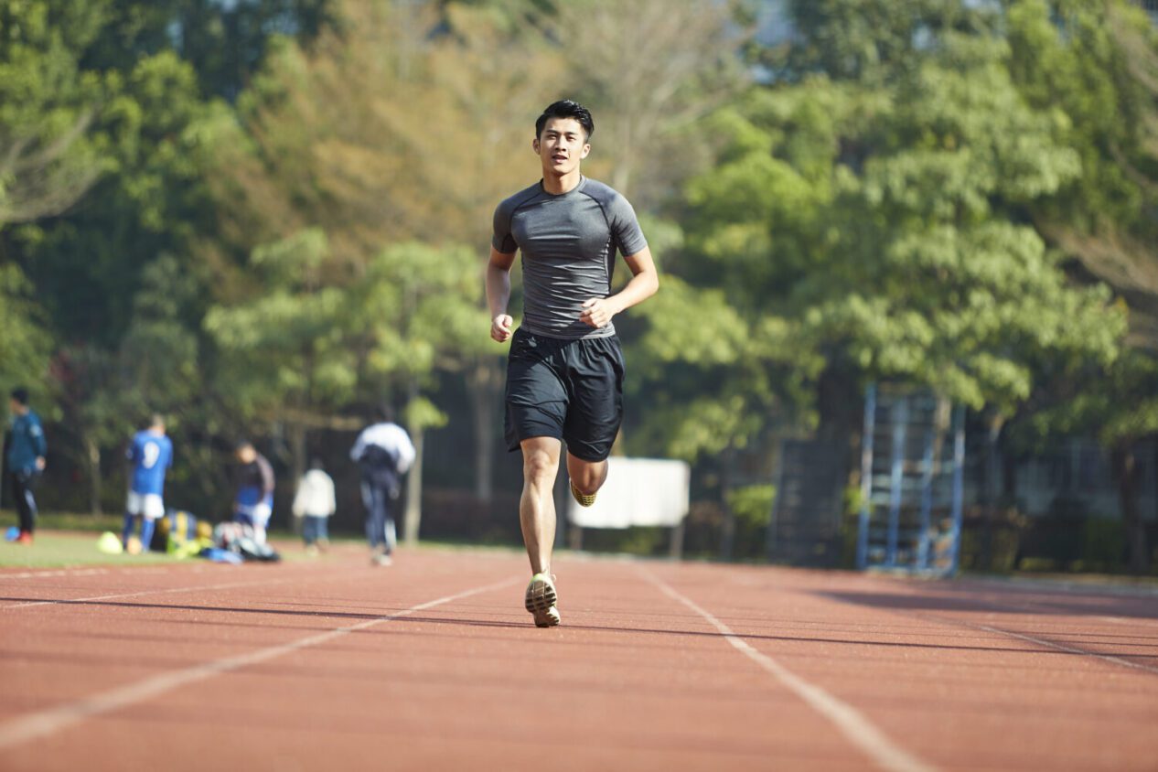 young asian man male athlete running training exercising on track