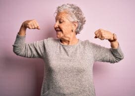 Senior beautiful woman wearing casual t-shirt standing over isolated pink background showing arms muscles smiling proud. Fitness concept. Aaron Amat/iStock