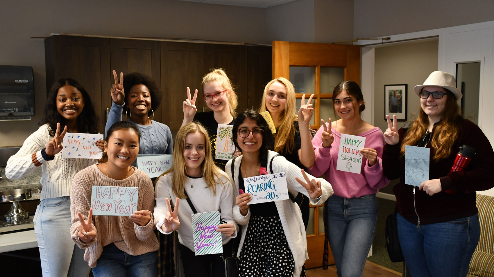 Students from USC Glamour Gals smiling and holding peace signs with handmade cards for the holiday season