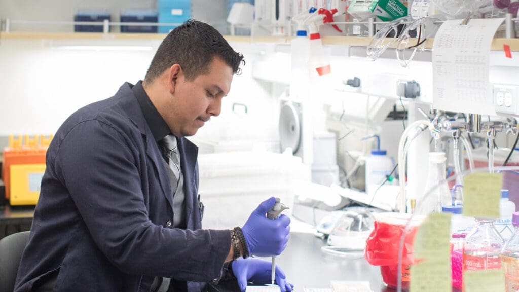 Juan Bravo injecting something into tubes in a lab