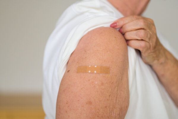 Older adult with bandage on shoulder after receiving a vaccine